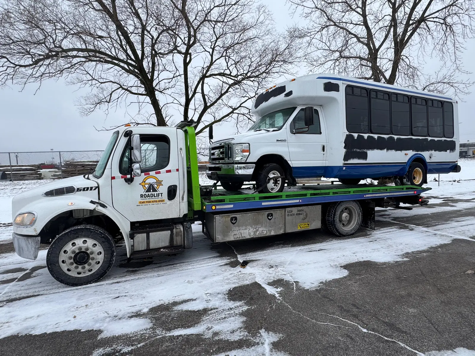 Medium-duty towing service in Oak Lawn, IL by RoadLift Towing & Recovery, transporting a commercial shuttle bus safely on a flatbed tow truck.