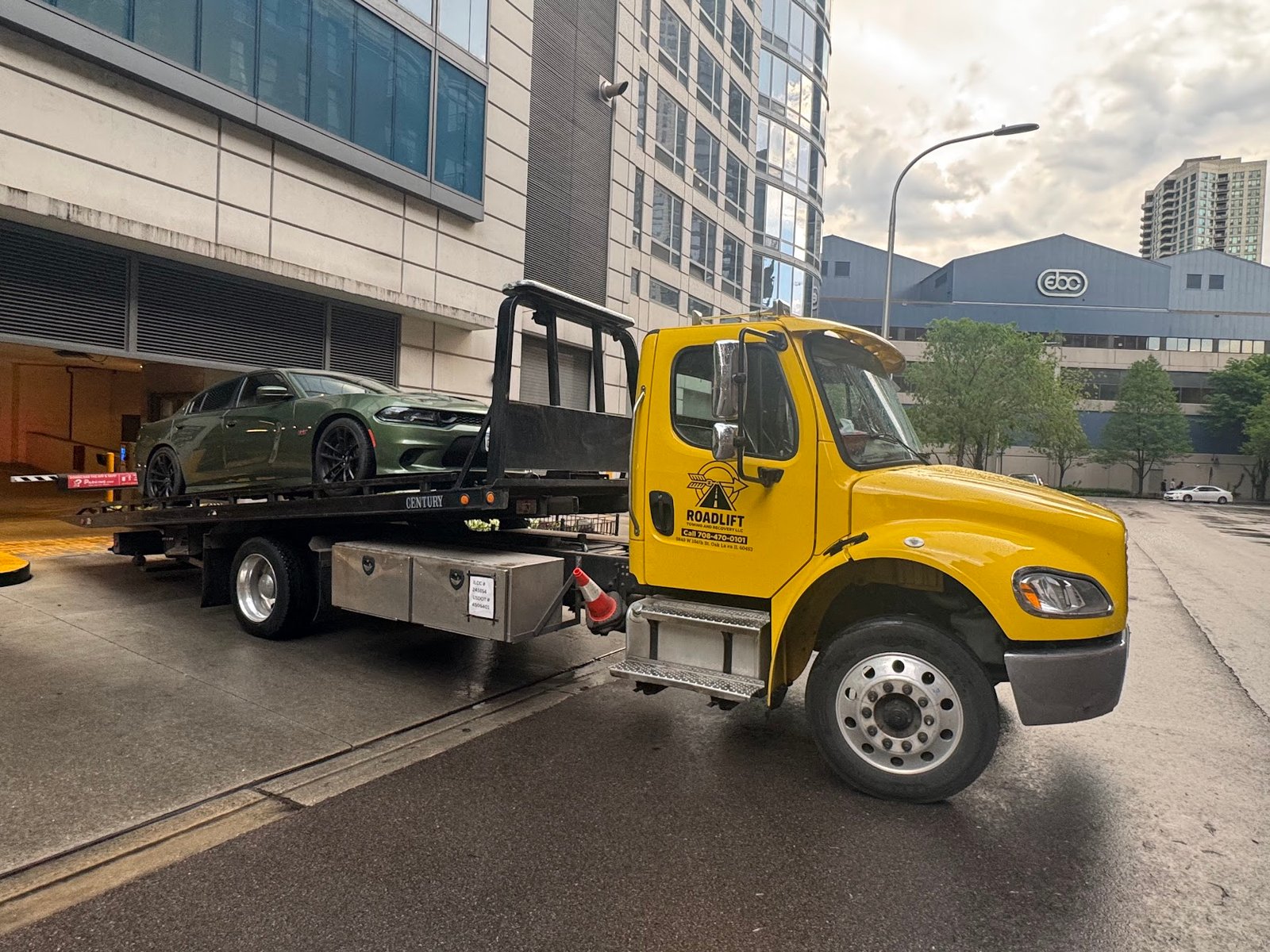 RoadLift Towing flatbed tow truck transporting a black pickup truck in the Chicago area